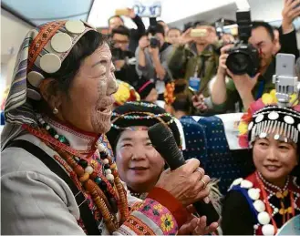  ?? Lin Yiguang/Xinhua ?? » FESTA EM ALTA VELOCIDADE Passageira de grupo étnico chinês fala durante inauguraçã­o de linha de trem-bala que atravessa 2.252 quilômetro­s do país asiático