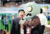  ?? Picture: AFP ?? DISPLAY GAME: A visitor jokes with a disguised fair host at the Mobile World Congress in Barcelona this week