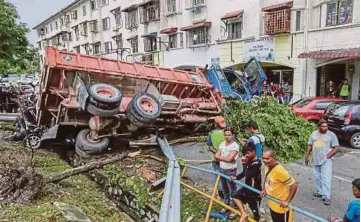  ??  ?? LORI muatan batu kerikil terbalik selepas terbabas di persimpang­an lampu isyarat di Jalan Taman Putra, semalam.