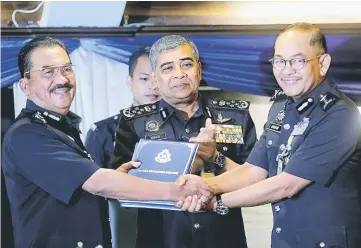  ??  ?? Khalid (centre) looks on as Jalaluddin (left) hands over documents to Abdul Ghafar who was appointed Director of Integrity and Standard Compliance Department. — Bernama photo