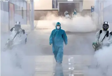  ??  ?? Volunteers disinfect a railway station in Wuhan province, China.