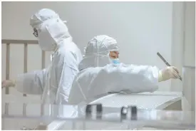  ??  ?? ◀ Staff inspect the sterile needles and syringe bottles for the COVID- 19 vaccine.