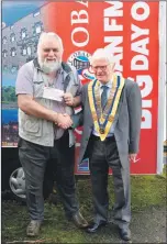  ??  ?? Rotary Club of Oban President Douglas Small hands over a cheque for £780 to Oban FM stalwart and chairperso­n Campbell Cameron to help buy the Big Day Out trailer.