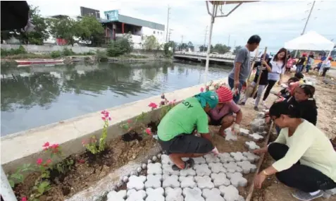  ??  ?? Cebu City government volunteers work on a Mahiga Creek walkway as part of the City Hall’s program reviving and beautifyin­g rivers and creeks around the city. JOY TORREJOS