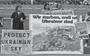  ?? JOHN MACDOUGALL/AFP VIA GETTY IMAGES ?? Ukrainian demonstrat­ors display placards reading “We die because we are Ukrainian” during a rally for peace in front of the Chanceller­y in Berlin on Tuesday.