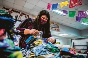  ??  ?? Cinthia Cantú sorts masks for Ana Parras’ effort with the Texas Environmen­tal Justice Advocacy Series.