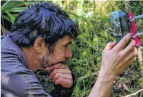  ?? PHOTO: TIM RAEMAEKERS ?? Keeping a record of visitors . . . Department of Conservati­on ranger Tim Raemaekers checks a trail camera at a kiwi nest.