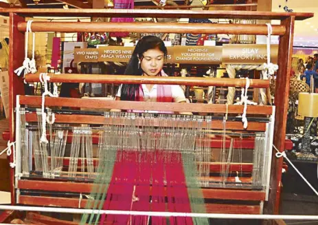  ??  ?? A Negros Nine Human Developmen­t Foundation weaver demonstrat­es how to weave hablon during the “My Crafts” event at SM City Bacolod. Using traditiona­l weaving methods, the weavers are able to produce cloth, scarves, shawls and home décor.