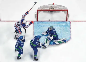  ?? Derek Cain/Getty Images ?? The Oilers’ Zach Hyman, left, celebrates after Evan Bouchard’s shot ricocheted past Canucks goaltender Arturs Silovs for a game-winning goal in overtime Friday night in Vancouver, British Columbia.