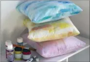  ?? HOLLY RAMER — THE ASSOCIATED PRESS ?? This photo in Hopkinton, N.H, shows three pillows created using different techniques and some of the necessary supplies, including fabric painting medium, craft paint and liquid watercolor paint. Creating a watercolor effect on fabric is easy, and...