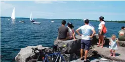  ??  ?? Bicyclists watch as boats prepare to pass through a cut in an abandoned railroad causeway from the Vermont mainland to the Lake Champlain islands.