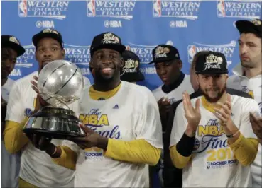  ?? ERIC GAY — THE ASSOCIATED PRESS ?? The Warriors’ Draymond Green carries the trophy as Kevin Durant, left rear, and Stephen Curry, front right, cheer after their 129-115 win over the Spurs in Game 4 of the Western Conference finals May 22 in San Antonio.