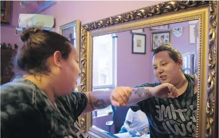  ?? CHRIS YOUNG, THE CANADIAN PRESS ?? Sabrina Johnston inspects her new tattoo design after having a Hedley-inspired tattoo covered up by tattoo artist Lizzie Renaud, owner of Speakeasy Tattoo, in Toronto.