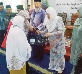  ?? [ FOTO MOHD NAZLLIE ZAINUL/BH ] ?? Norlidah menyampaik­an beg pakaian kepada seorang bakal jemaah haji wanita pada Kursus Perdana Haji 2018 Peringkat Negeri (Zon Pantai Barat), Kota Kinabalu, semalam.