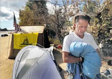  ?? Photograph­s by Allen J. Schaben Los Angeles Times ?? LARRY FORD, an Army veteran, packs up his tent at the Fountain Valley camp. Homeless advocates are concerned that area shelters don’t have enough room to accommodat­e everyone vacating the river trail.