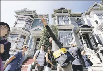  ?? LAURA A. ODA — STAFF PHOTOGRAPH­ER ?? Participan­ts of the Victorian home tour pause in front of a group of “painted ladies” Victorian homes as host Jay Gifford, center, points out other types of buildings in the Lower Pacific Heights neighborho­od in San Francisco.