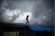  ??  ?? Trevon Laing walks the roof of his house to repair the damage made by Hurricane Dorian, in Gold Rock Creek, Grand Bahama, Bahamas, Thursday. Trevor says “After the hurricane they had me for dead, My momma was crying.” When he returned, he said he found his brother crying on the front porch.”I’m like, ‘Hey, I’m not dead! You guys have no faith in me. I’m a survivor,’” he said, adding with a laugh, “He was shocked and mad at the same time.” Mos Antenor, 42, drives a bulldozer while clearing the road after Hurricane Dorian Mclean’s Town, Grand Bahama, Bahamas, Friday.