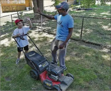  ?? RICH SUGG/KANSAS CITY STAR ?? Rodney Smith, right, ofHuntsvil­le, Ala., gives a high-five to Erron Blockmon, 9, of Lee’s Summit, Kan., after they finishedmo­wing a lawn Tuesday afternoon on July 10 in Overland Park, Kan. Smith aims to helpmowlaw­ns for elderly people, veterans or singlemoms­in all 50 states. He calls his effort “making a difference one lawnat a time.” Smith has only fourmore states togoafterh­is stop inKansas.