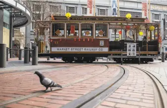  ?? Jessica Christian / The Chronicle ?? A cable car adorned in Lunar New Year decoration­s parked for photo opportunit­ies at the turnaround at Powell and Market streets in February. The cable cars remain out of operation.