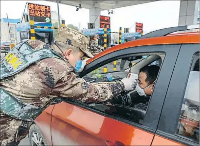  ?? STRINGER / EFE ?? Un militar toma la temperatur­a a un conductor que pretende salir por autopista de Wuhan