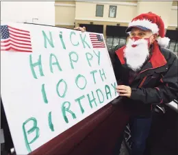  ??  ?? Leon Breault, of Norwalk, adds a sign to his car for the drive-by 100th birthday parade.