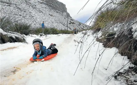  ?? Picture: SHELLEY CHRISTIANS ?? Camden Harwood slides down an icy slope in the Matroosber­g area near Ceres after a push from his father, Johan, kneeling. A cold front this week deposited snow on mountain peaks across the Western Cape and Northern Cape