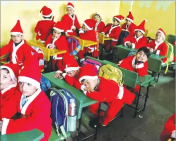  ?? — Reuters ?? Children dressed in Santa Claus costumes sit inside a classroom before participat­ing in Christmas celebratio­ns at a school in Chandigarh, India, last Thursday.