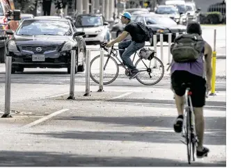  ?? RODOLFO GONZALEZ / AMERICAN-STATESMAN ?? Standing pylons separate traffic from a dedicated two-way bike lane for cyclists commuting Thursday along Rio Grande Street in Austin. Full funding of Austin’s bicycle master plan, a $151.7 million endeavor, was the most frequent suggestion in the...