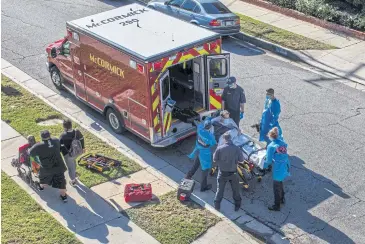  ?? AFP ?? Los Angeles paramedics load a potential Covid-19 patient before transporti­ng him to a hospital on Dec 29.