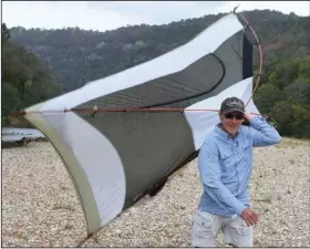  ?? (Arkansas Democrat-Gazette/Bryan Hendricks) ?? Dick Phelan of Benton carries a wayward tent across a gravel bar in heavy wind Monday.