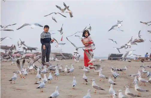  ?? Associated Press ?? Children feed gulls by the banks of the Ganges in Prayagraj, India, on Thursday.