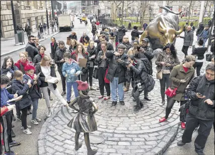  ?? MARK LENNIHAN PHOTOS / AP ?? A crowd gathers around a statue of a fearless girl facing the Wall Street bull on Wednesday in New York. The statue was installed by an investment firm to mark Internatio­nal Women’s Day.