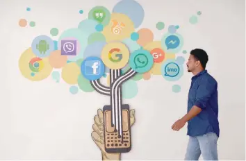  ??  ?? A visitor passes a mural depicting various social media including Facebook, inside a building in Bangalore on Thursday. — AFP