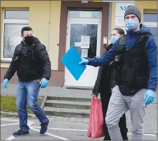  ?? (AP/Czarek Sokolowski) ?? Polish Border Guard officers escort a Syrian woman from a hospital Monday in Bielsk Podlaski. The woman suffered a miscarriag­e after being trapped in a forest in Poland after crossing the border from Belarus, then she caught covid-19 while being treated in a hospital.