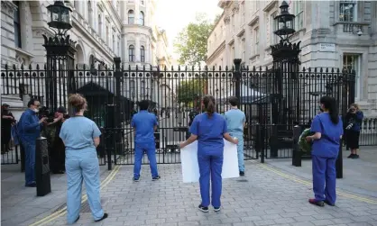  ?? Photograph: Anadolu Agency/Getty Images ?? Doctors involved in the fight against coronaviru­s protest outside the gates of Downing Street.