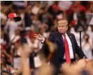  ?? Photograph: Joe Raedle/ Getty Images ?? Donald Trump tosses a Maga cap into the crowd in Sunrise.