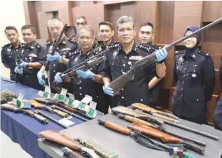  ??  ?? Asri (right) and his officers showing the shotguns confiscate­d from 14 individual­s held in connection with the theft of 26 shotguns from Rela Northern Region Training Centre in Selama, Perak.