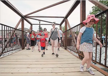  ?? PETER LEE WATERLOO REGION RECORD ?? Walking tall! Eager pedestrian­s can’t wait to try out the new bridge after the official opening. Crystal Lemos, centre, holds the hand of her four-year-old son Carter.