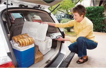  ?? Jerry Baker ?? Sherry Blattel of The Woodands loaded up for a delivery several years ago at the South County Community Center. While bringing well-balanced meals to seniors in need is the primary mission of Meals on Wheels, most volunteers use the drop-off time to...