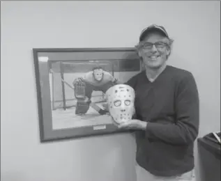  ?? COURTESY OF DENNIS KEMP ?? Dennis Kemp, the long-anonymous model for Ken Danby’s ‘At The Crease,’ in front of a print of the painting. He is holding a model of the mask he was wearing when Danby took his photo in 1972.