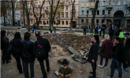  ?? ?? People gather by a rocket crater in central Kyiv on Wednesday after Russian strikes two days earlier. Photograph: Dimitar Dilkoff/AFP/ Getty Images