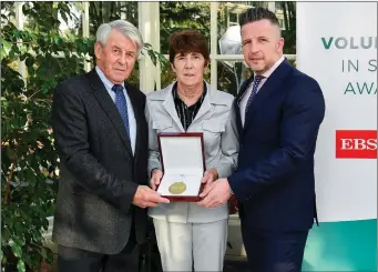  ??  ?? Theresa Kinane of Greystones AC is presented with their award by Roddy Guiney, Chairperso­n of the Federation of Irish Sport, left, and Richard Gernon, Regional Manager EBS, during the Volunteers in Sport Awards presented by Federation of Irish Sport with EBS at Farmleigh House in Phoenix Park in November of 2019.