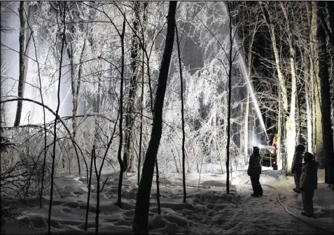  ?? JOE KLEMENTOVI­CH PHOTOS / HUBBARD BROOK RESEARCH FOUNDATION VIA AP ?? A firefighti­ng hose mounted on an ATV sprays water on trees in the Hubbard Brook Experiment­al Forest in Woodstock, N.H. Scientists have been creating ice storms there to help understand the effects of ice on northern forests.