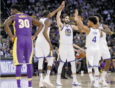  ?? Photos by Scott Strazzante / The Chronicle ?? Kevin Durant, Omri Casspi, Quinn Cook and Nick Young high-five in the fourth quarter. Missing three starters, the new-look lineup managed to keep Golden State from losing three in a row for the first time this season.