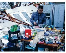  ?? BILL LACKEY / STAFF ?? Shoji Uota pours his dog some fresh water after finding the dog’s bowl in what remains of his kitchen after Wednesday’s storm destroyed his house on Ridge Road in Clark County.