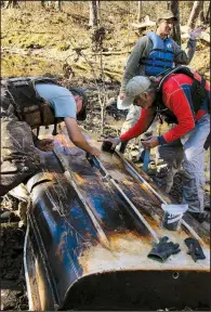  ??  ?? Applying layers of epoxy and glue, Cowper Chadbourn (from left), Roger Head and Mike Sprague patch a wrecked fiberglass boat they found washed up in tree debris during an Arkansas Canoe Club Black OPs Advanced Trash Removal outing Nov. 24 on Cadron Creek.