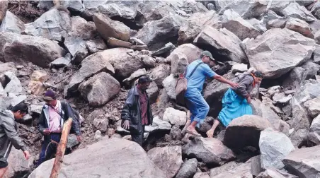  ??  ?? People trek through the boulders that landed near the bridge in the landslide at Kuderachol­a in Nelliyampa­thy.