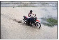  ?? AP/AARON FAVILA ?? A motorcycle rider crosses a flooded area Friday in the northeaste­rn Philippine­s city of Tuguegarao.