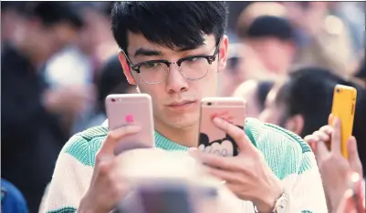  ?? XU KANGPING / FOR CHINA DAILY ?? A man plays with his mobile phones in Hangzhou, Zhejiang province.