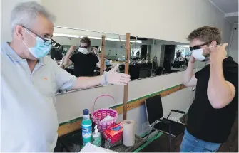  ??  ?? Customer Jack Postmus puts on a mask before getting his haircut at Soussan's Barber Shop in Kingston, Ont., on Friday. Rising costs are boosting the prices of masks.